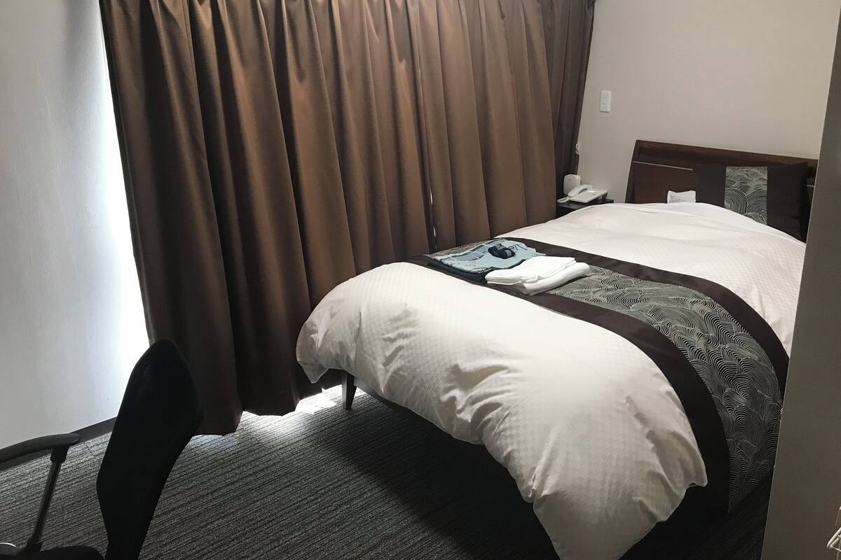 Ein Hotelzimmer mit Bett, Sessel, Schreibtisch und Telefon.