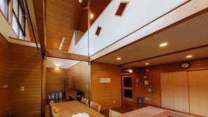 A wooden interior with a dining area, a small kitchen, and a wooden door. - Cottage Villa Top (Shintotsukawa)