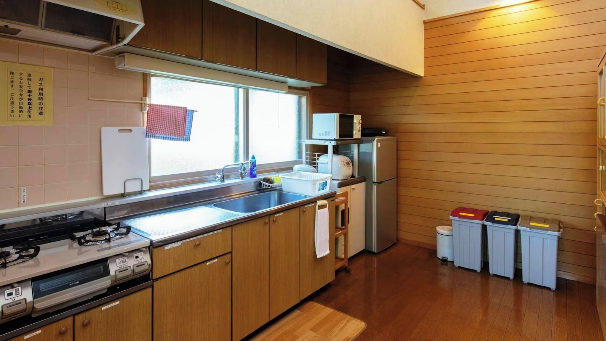 Une cuisine de taille réduite, dotée de meubles en bois, d’un évier en acier inoxydable, d’une cuisinière et d’un four à micro-ondes.