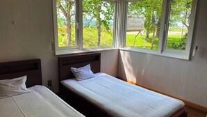 A bedroom with two beds, a window with a view of greenery, and a wooden headboard. - Cottage Villa Top (Shintotsukawa)