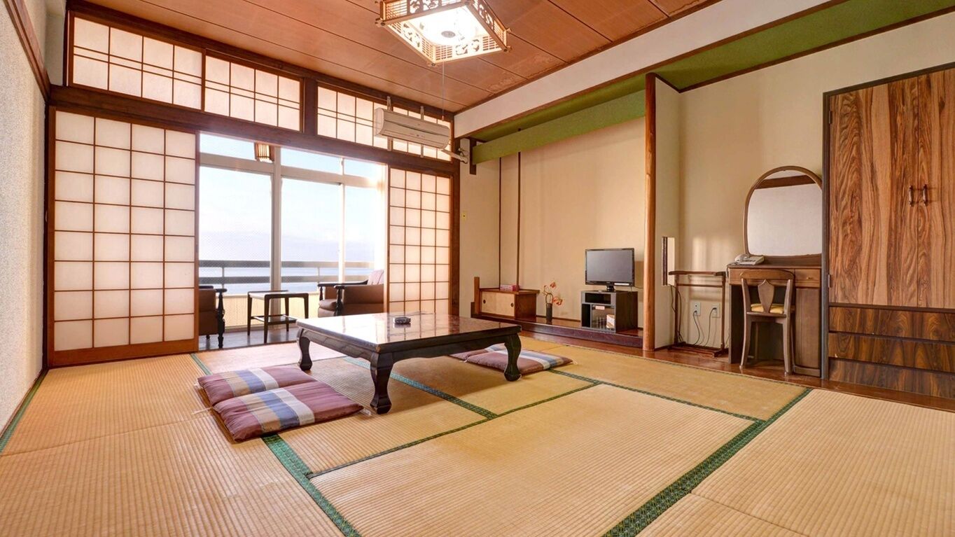 Habitació japonesa tradicional amb tatami, una taula baixa, televisió i un mirall gran.