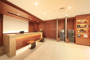 A hotel reception area with a marble counter, wooden paneling, a reception desk, a bench, and a wall-mounted sign. - Richmond Hotel Nagoya Shinkansenguchi (Nagoya)