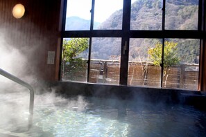 A hot spring area with a wooden interior and a view of a mountainous landscape through large windows. - Minami Alps Seitaimura Healthy Misato (Hayakawa)