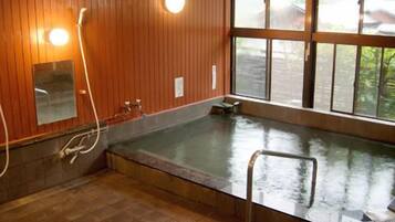 Une pièce avec une grande baignoire, des murs en bois, une fenêtre et un miroir.