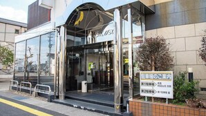 A modern building with a glass entrance and a sign indicating parking areas. - Hotel Primrose Saito (Saito)