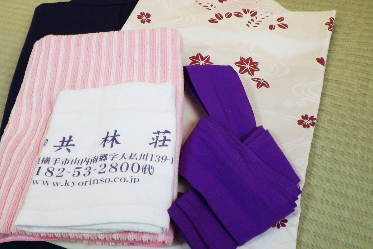 A folded towel and a purple cloth item on a patterned fabric.