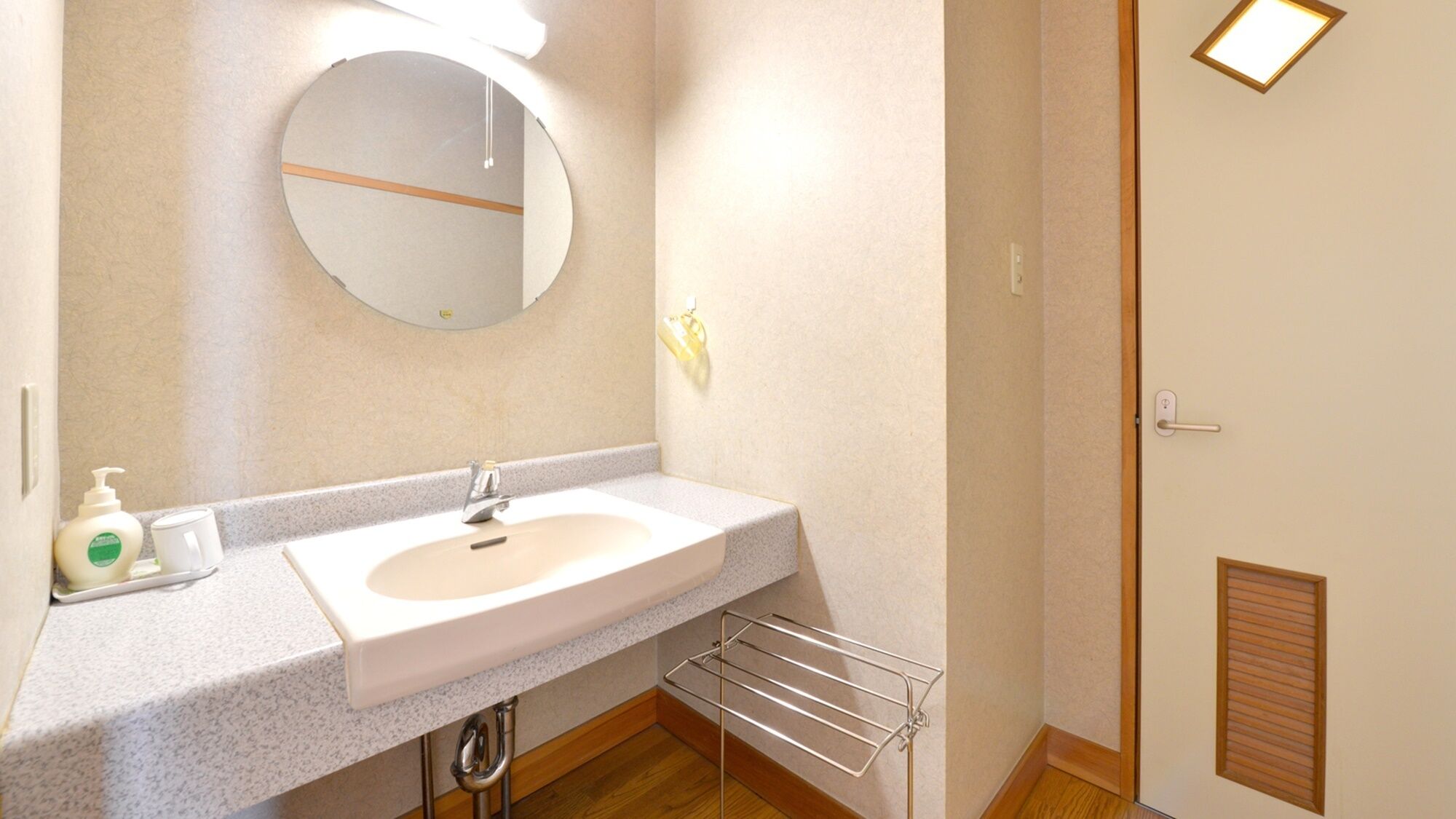 A bathroom with a sink, mirror, towel rack, and toiletries.