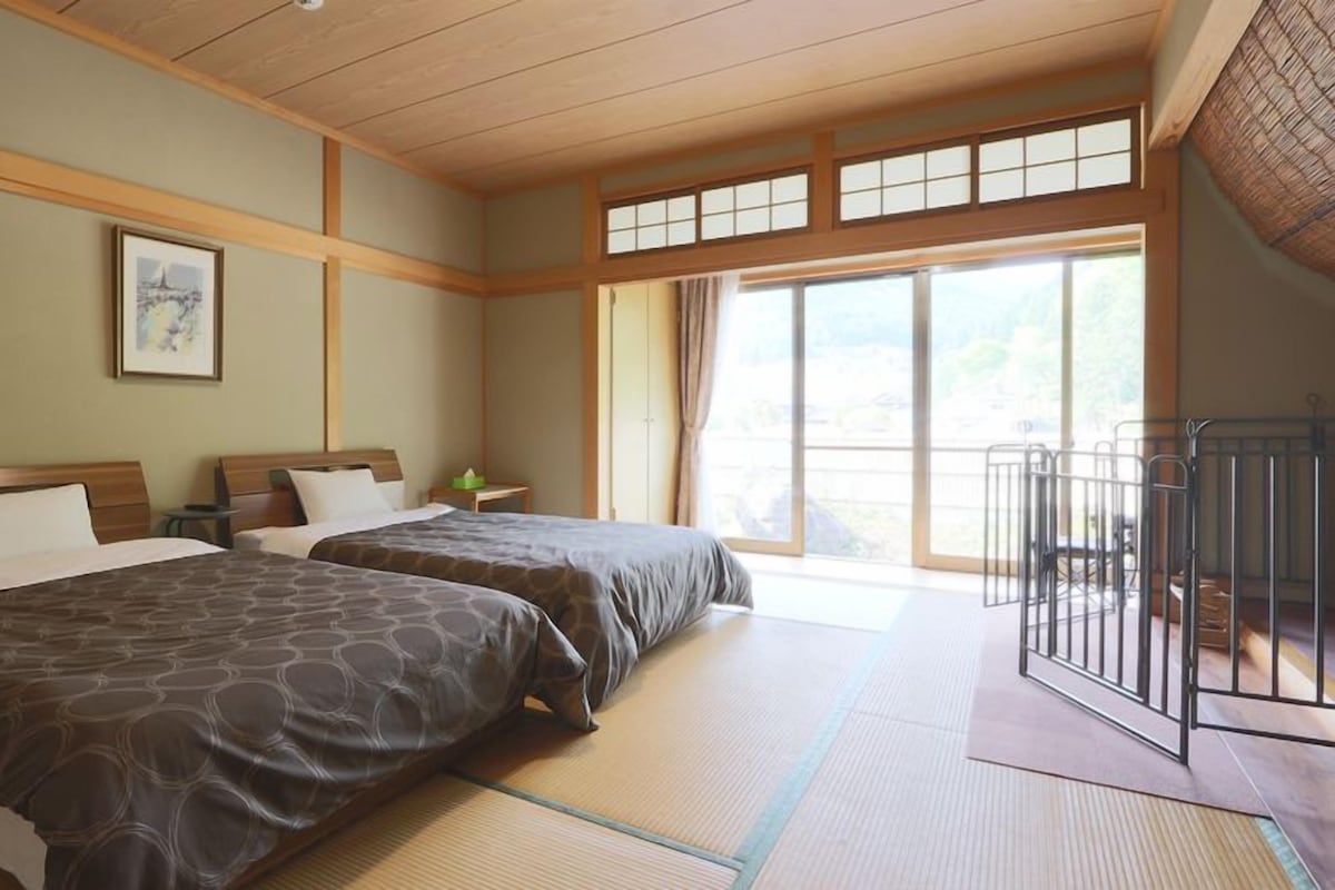A hotel room with two beds, a large window, and a balcony with a railing.