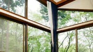 A room with a wooden table, chairs, and a view of trees through large windows. - Hotel Silk Villa (Kimitsu)