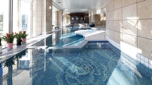 A large indoor swimming pool with a tiled floor and a hot tub area.