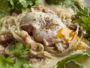 A close-up of a dish with pasta, a poached egg, and bacon garnished with herbs. - THE FARM Resort Japan (Katori-shi)