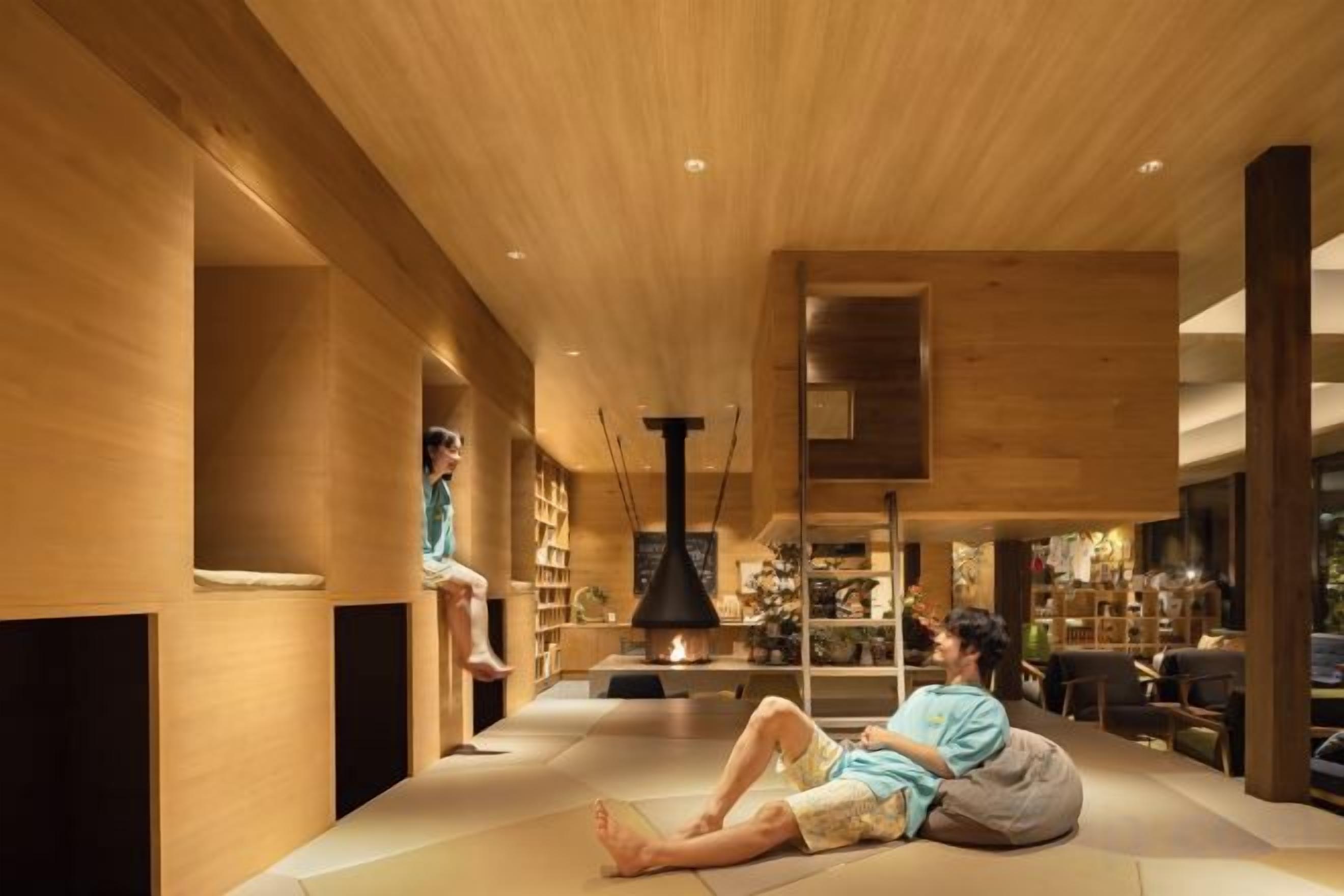 A modern interior with a wooden ceiling, a fireplace, and a person sitting on the floor.