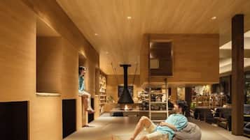A modern interior with a wooden ceiling, a fireplace, and a person sitting on the floor.