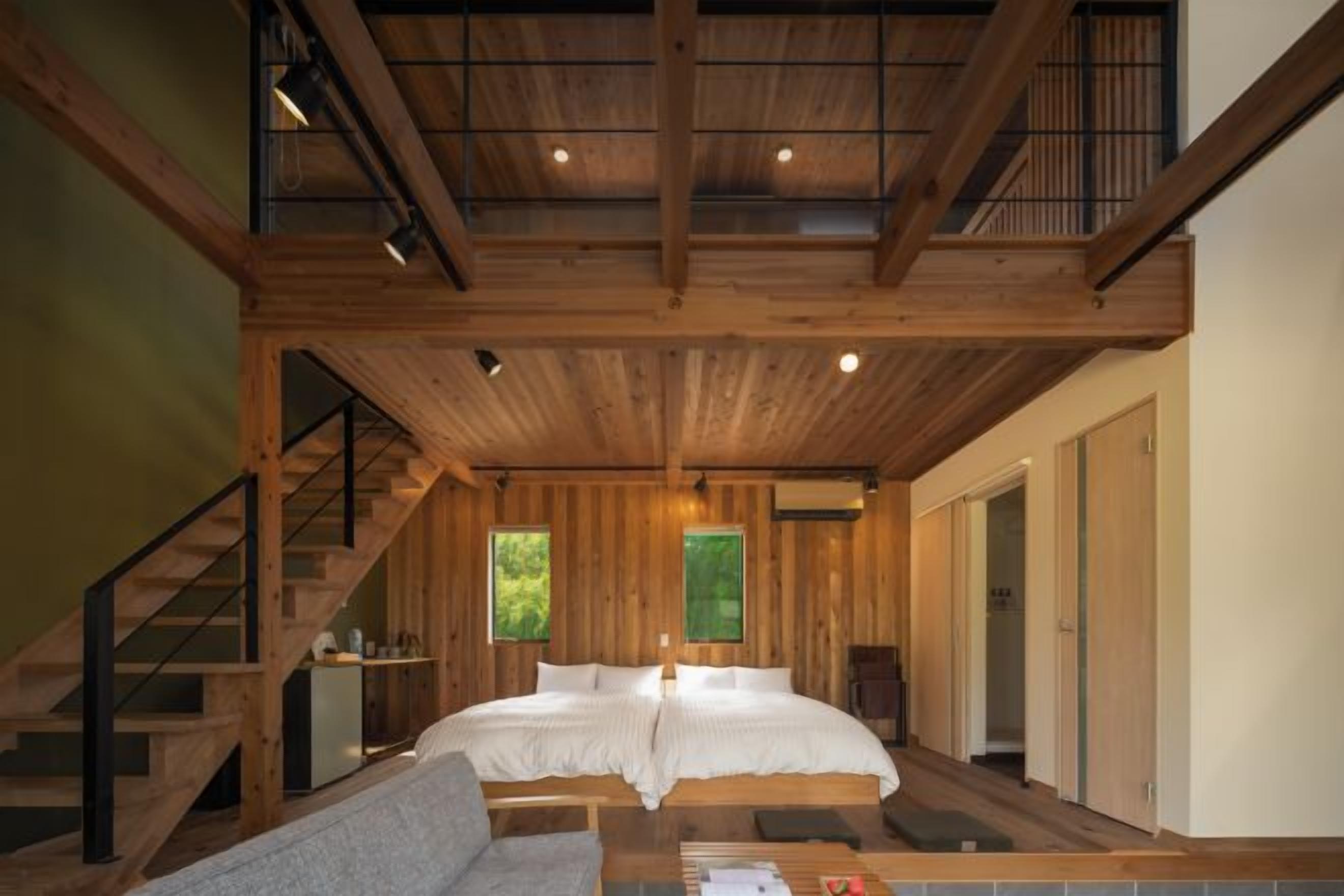 Interior de madeira com cama, escada e um pequeno espaço para sentar.