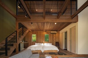 A wooden interior with a bed, staircase, and a small seating area.