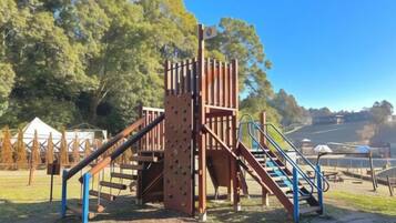 A playground with a climbing structure and slides.