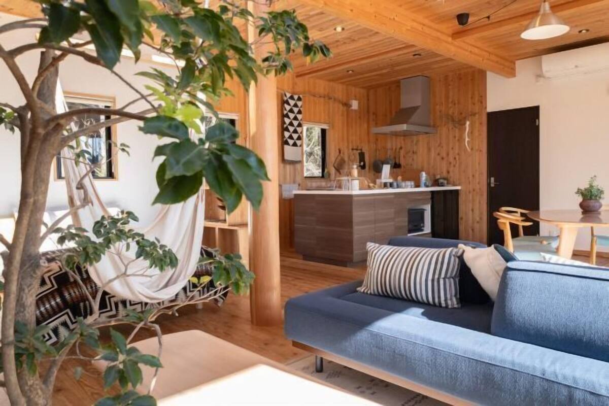 A modern interior with a blue sofa, wooden ceiling, and a dining area.