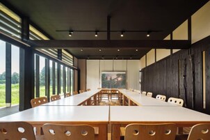 Un salón de conferencias con una larga mesa y sillas, ventanas amplias y vistas al exterior.