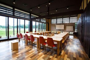 A conference room with a long table, red chairs, and a projector screen. - THE FARM Resort Japan (Katori-shi)