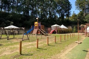 A playground with various play structures, including slides and swings, surrounded by a fenced area. - THE FARM Resort Japan (Katori-shi)