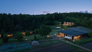 Un hôtel moderne doté d’un grand bâtiment central et de plusieurs petites annexes, le tout entouré d’une zone boisée.
