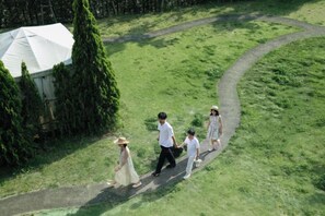 A group of people walking on a grassy path with a tent and trees in the background. - THE FARM Resort Japan (Katori-shi)
