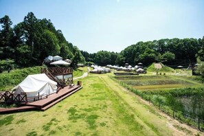 A campsite with tents and a covered area, surrounded by greenery and fields. - THE FARM Resort Japan (Katori-shi)
