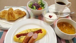 A breakfast setting with croissants, a salad, a cup of coffee, a bowl of soup, and a plate with eggs and sausages. - Narita no Mori Country Club (Katori)