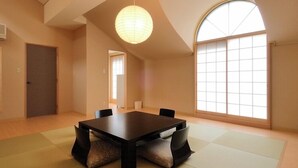 A room with tatami mats, a dark wooden table, chairs, a paper lantern, and a large window. - Narita no Mori Country Club (Katori)