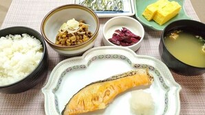A meal with rice, miso soup, pickled vegetables, and a fish.