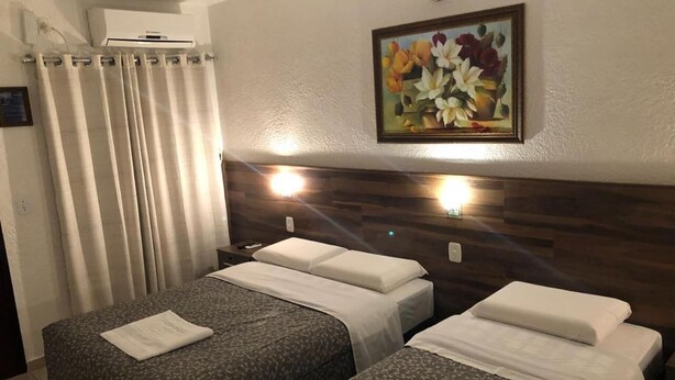 Habitación de hotel con dos camas, un cuadro en la pared y un equipo de aire acondicionado.