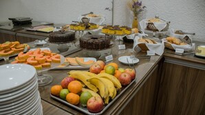Un bufé con diversas opciones de comida, incluyendo frutas, pasteles y bollería.
