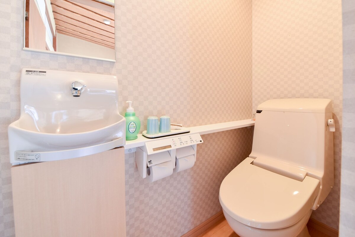 Une salle de bain avec un lavabo blanc, des toilettes et une étagère contenant des articles de toilette.