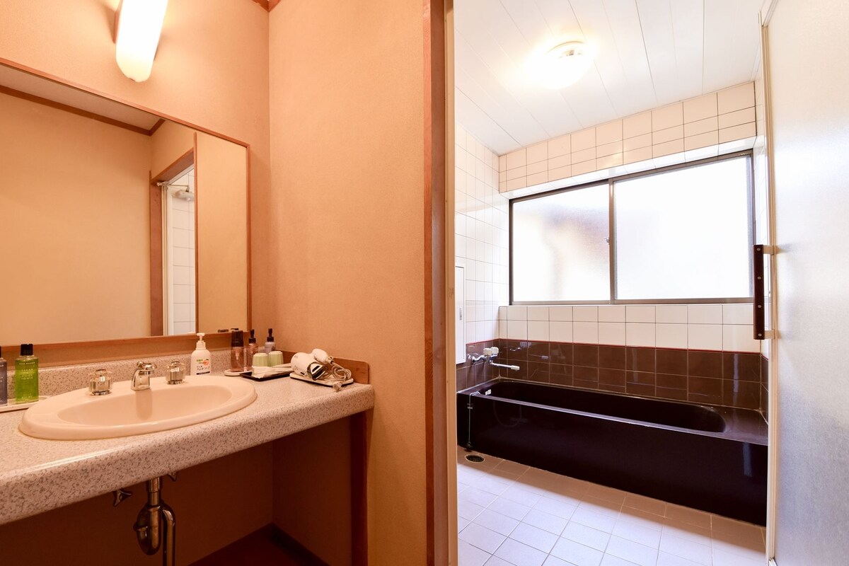 Une salle de bain équipée d’un lavabo, d’un miroir, d’articles de toilette et d’une baignoire.