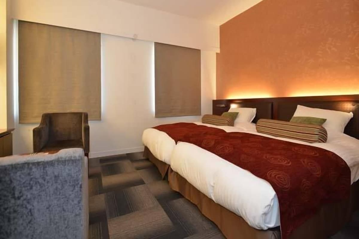 A hotel room with a large bed, a chair, and a window.