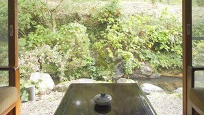 A room with a view of a garden, a table with a teapot, and a bench. - Yamae Onsen Hotaru (Yamae)