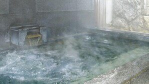 A hot spring bath with a stone wall and a wooden fence in the background. - Yamae Onsen Hotaru (Yamae)