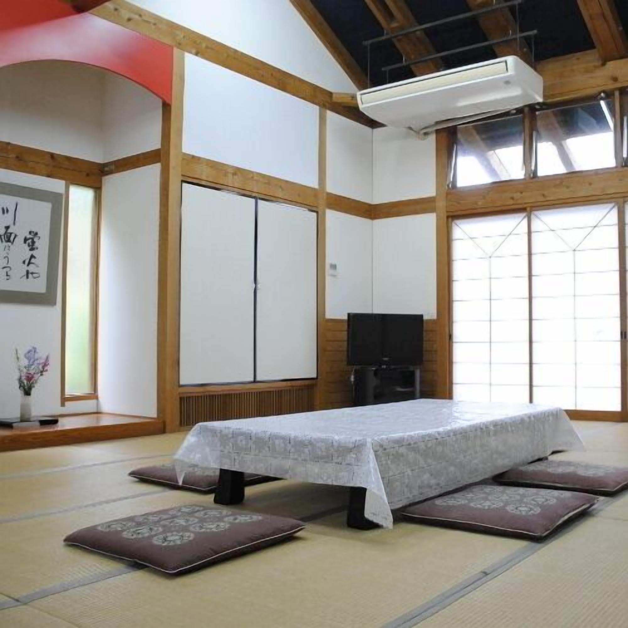 Een kamer met tatami matten, een tatami bed, een televisie en een schuifdeur.