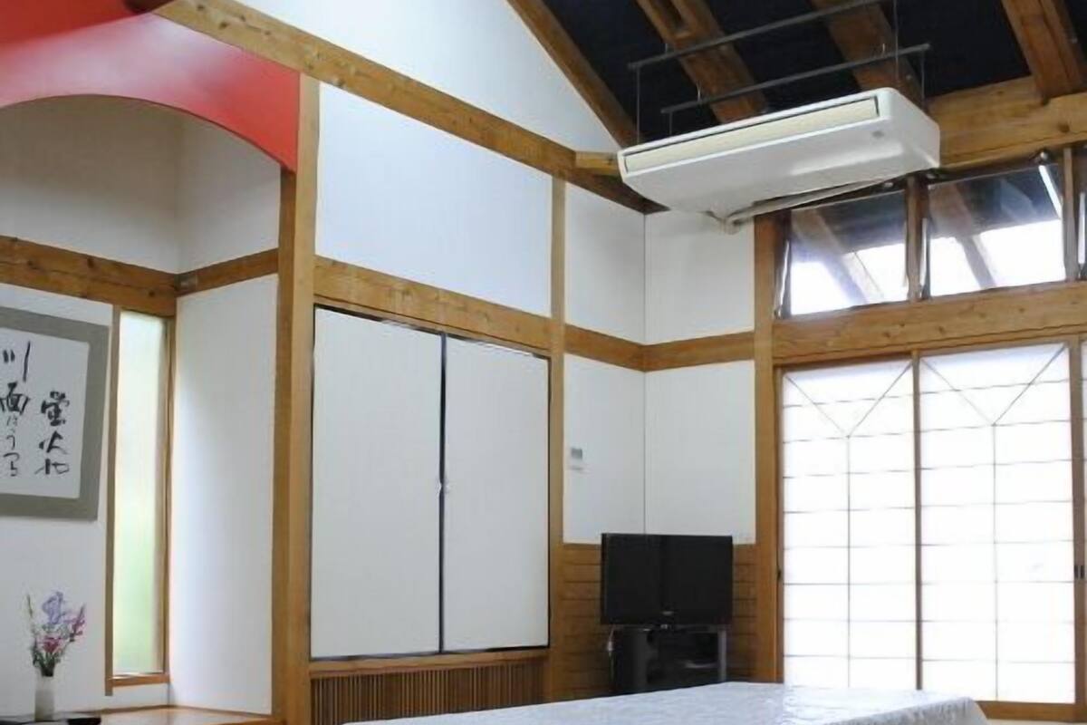 Una stanza con pavimento in tatami, un letto in tatami, una TV e un'anta scorrevole.