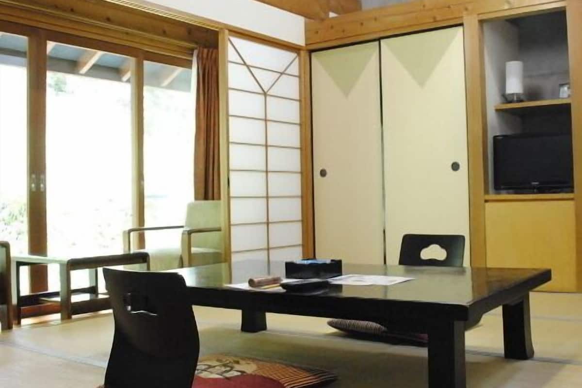 Una tradizionale stanza in stile giapponese con pavimento in tatami, un tavolino basso e porte scorrevoli.