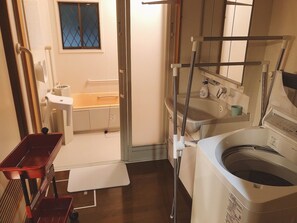 A compact bathroom with a bathtub, a sink, and a washing machine. - Kyoto Maizuru Fururu Farm Cottage (Maizuru)