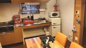 Cocina compacta con armarios de madera, microondas, tostadora y pileta.