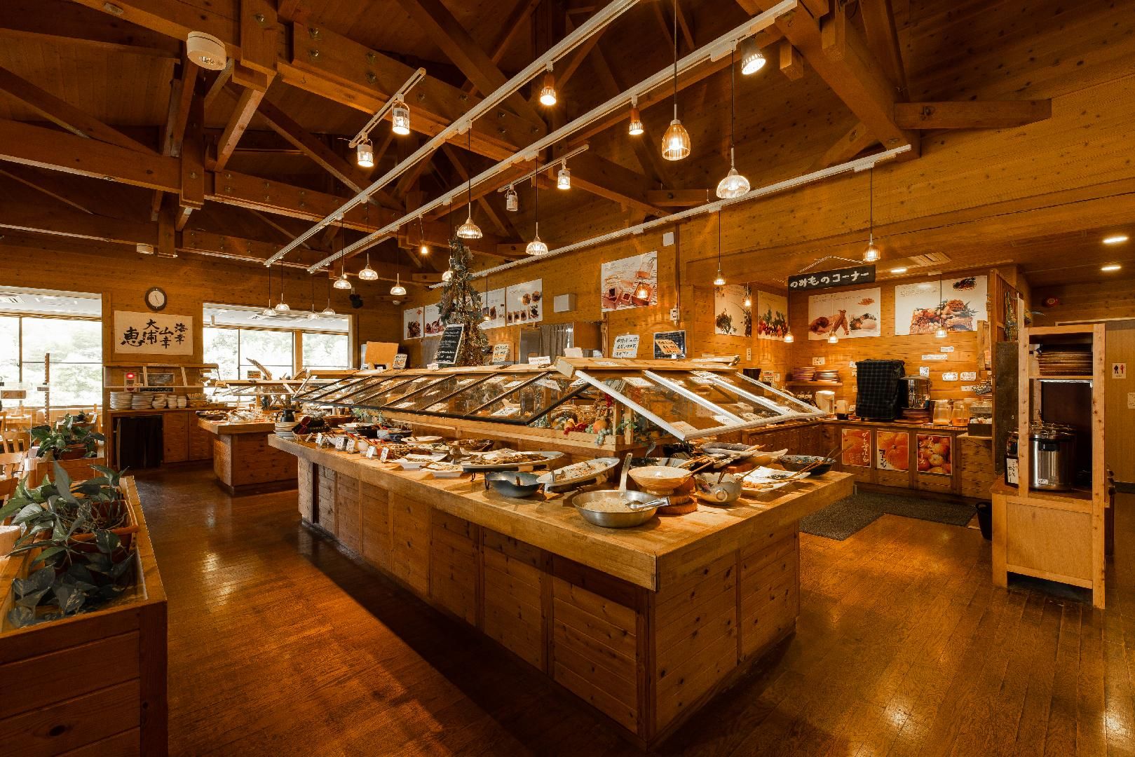 A restaurant with wooden interiors, a central buffet counter, and hanging pendant lights.