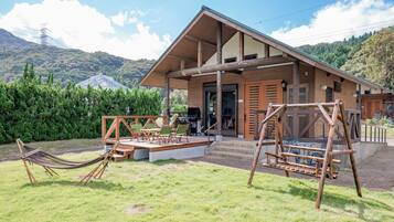 A wooden cabin with a porch, outdoor seating, and a hammock.