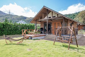 Une cabane en bois avec une véranda, des sièges d’extérieur et un hamac.