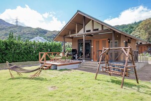 A wooden cabin with a porch, outdoor seating, and a hammock.