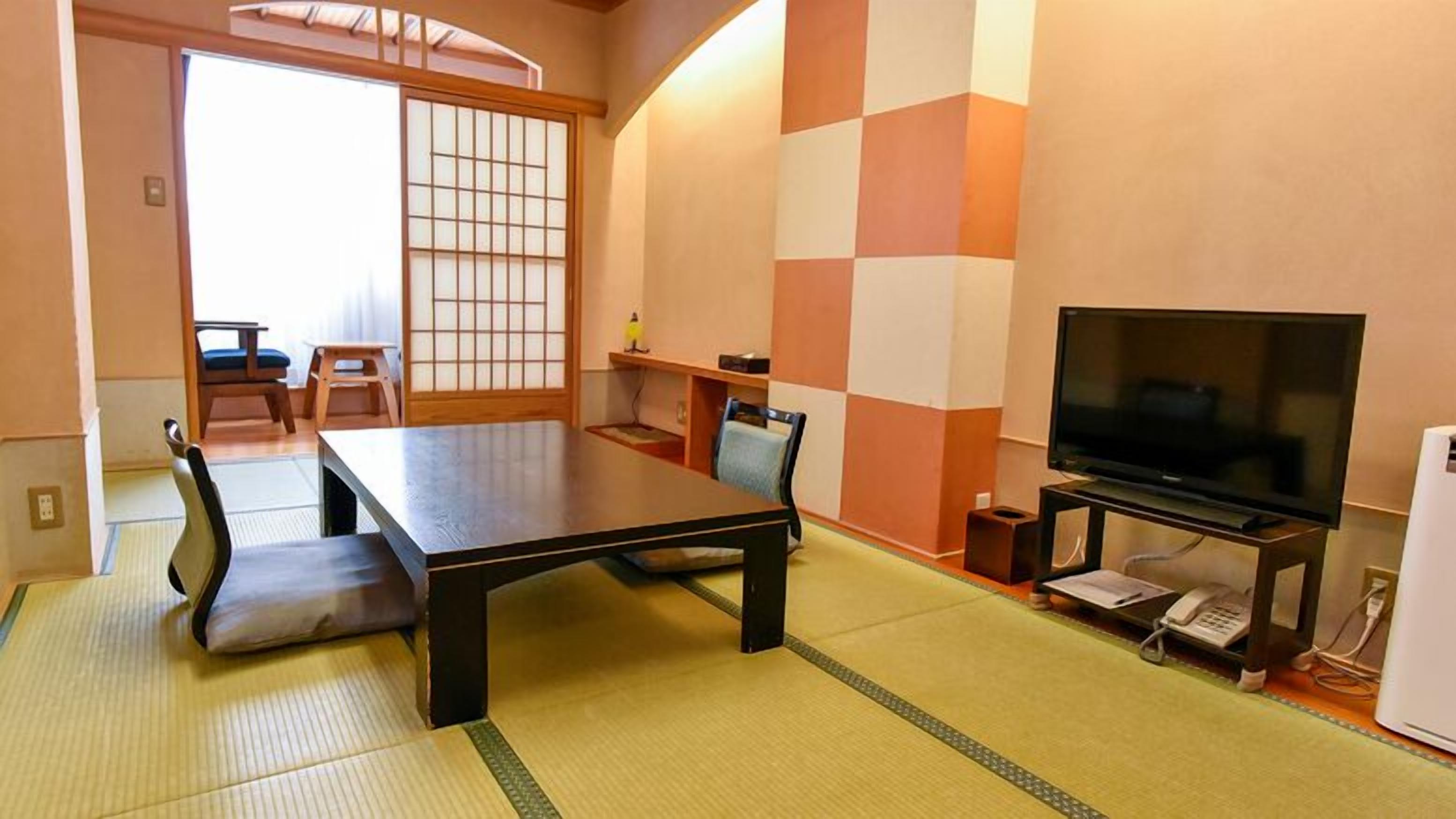 Perinteinen japanilaistyylinen huone, jossa on tatamimatto, matala pöytä, televisio ja liukuovi.
