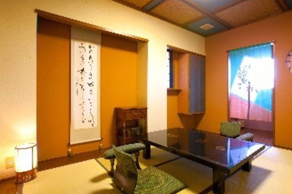 Une pièce avec une table en verre, des chaises, une porte coulissante de style japonais traditionnel, une fenêtre donnant sur un beau paysage et une horloge au mur.