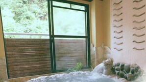 A room with a large window, a hot tub, and a wall with a unique design.