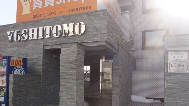 A building with a stone facade and a sign reading "Yoshitomo".